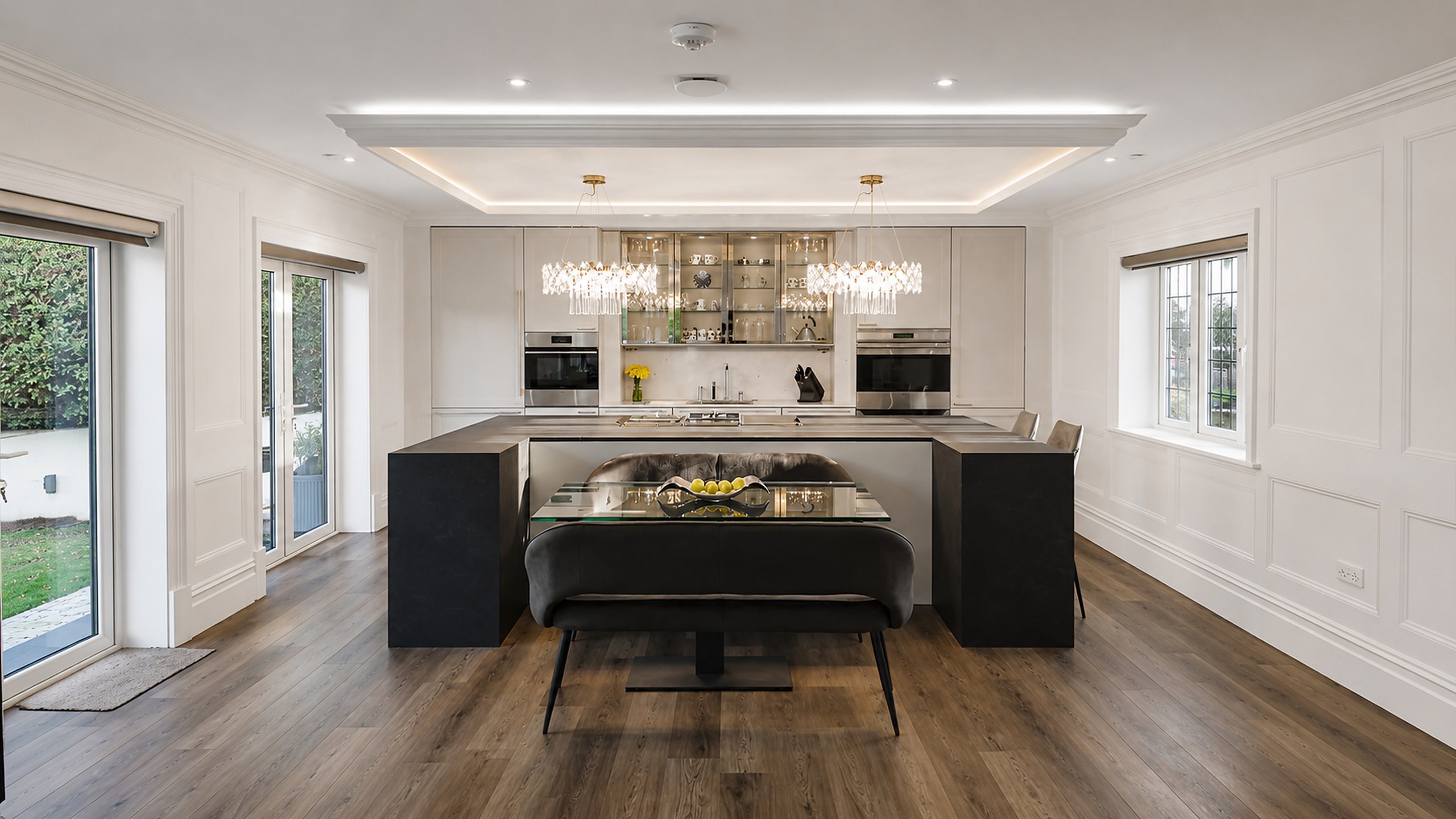 Fitted kitchen with a stone-topped island, glazed display cabinetry and panelled walls